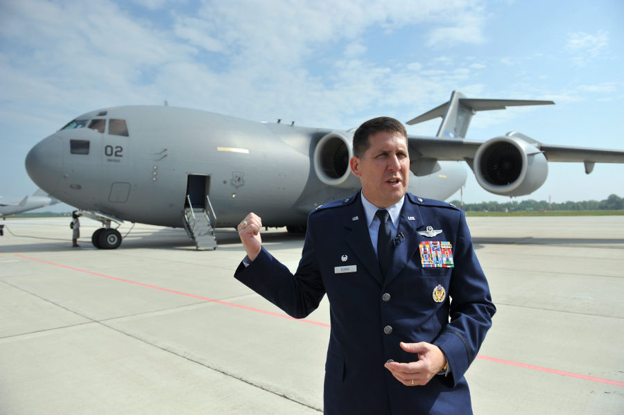 Keith Boon amerikai ezredes, a Neh&eacute;z L&eacute;gisz&aacute;ll&iacute;t&oacute; Ezred (Heavy Airlift Wing - HAW) parancsnoka egy Boeing C-17-es tehersz&aacute;ll&iacute;t&oacute; rep&uuml;lőg&eacute;p előtt &aacute;llva k&ouml;sz&ouml;nti az &uuml;nneps&eacute;gre &eacute;rkező vend&eacute;geket a p&aacute;pai b&aacute;zisrep&uuml;lőt&eacute;ren 