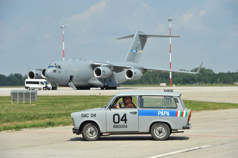 Egy Boeing C-17-es tehersz&aacute;ll&iacute;t&oacute; rep&uuml;lőg&eacute;p &eacute;s a kiszolg&aacute;l&oacute; szem&eacute;lyzet Trabant szem&eacute;lyg&eacute;pkocsija a p&aacute;pai b&aacute;zisrep&uuml;lőt&eacute;ren 